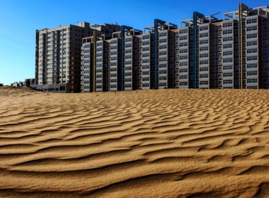 新建成的高层住宅楼在昔日滚滚黄沙之中矗立。