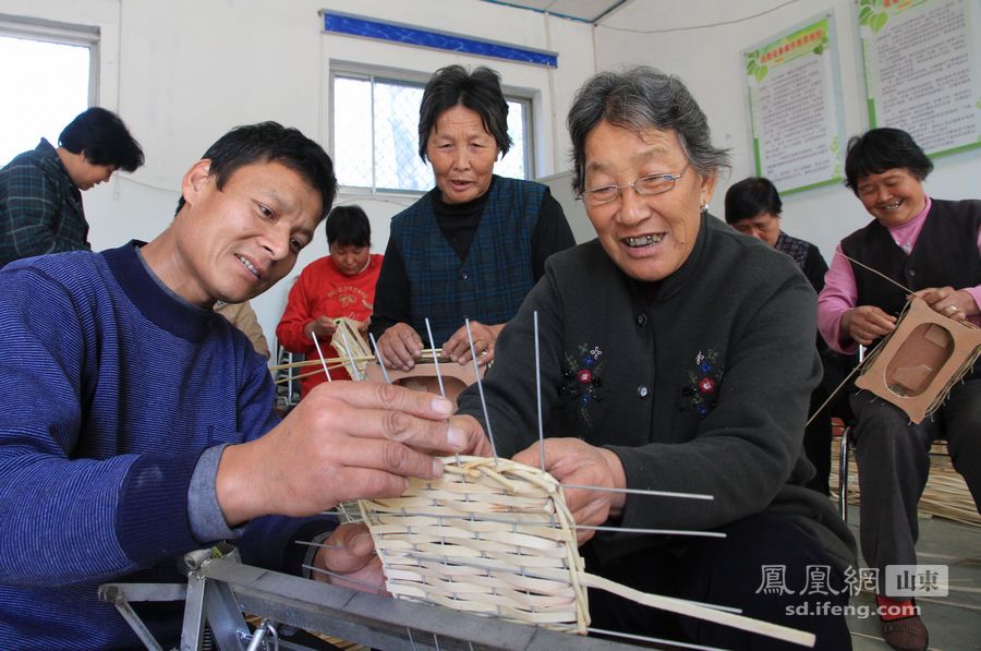 10月 24日，在山东省沂南县双堠镇东梭庄村，来自临沭的草编师傅张寿申（左）在教69岁的徐玉桂老人（右）编织工艺品。