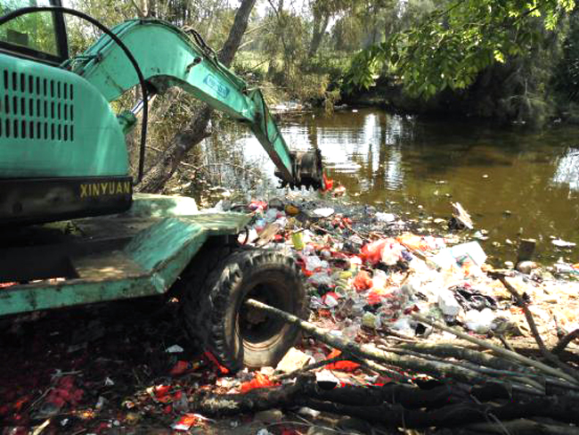 图为中和镇政府出动挖掘机清理七里村鱼塘边上堆积的陈年垃圾.