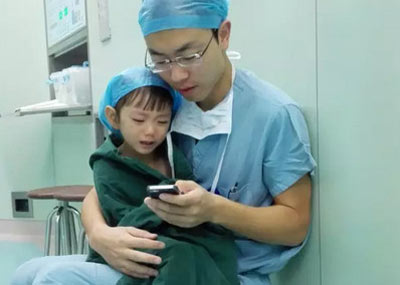 在心脏手术前，医生怀抱小姑娘安慰