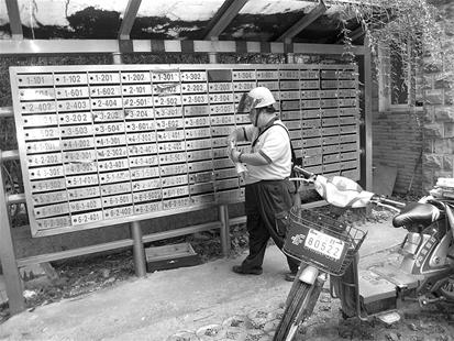 图为：邮递员洪军在投递。因为书信稀少，不少居民的收信箱长期空置。