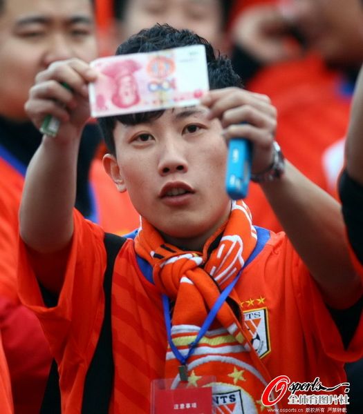 山东鲁能球迷挥舞钞票抗议足协 打横幅讽刺别