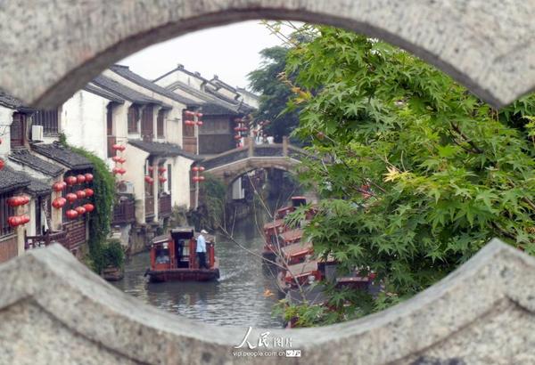 5月28日，载着游客的仿古游船在苏州山塘河驶行。炎炎夏日，姑苏“水上游”特色旅游项目成为许多中外游客消夏避暑的好选择。游客们乘船饱览姑苏“小桥、流水、人家”别有一番意境。（王建康/人民图片）