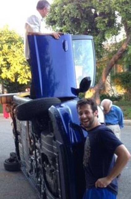 这对老夫妻开一辆蓝色本田轿车，在一条路上出事故后汽车左侧着地，幸运的是两人都没受伤。开车的妻子被困在了车里，而丈夫还能从座位上爬出来。于是在等待救援时，丈夫快活地站在翻倒的车外和他车里的妻子合影。