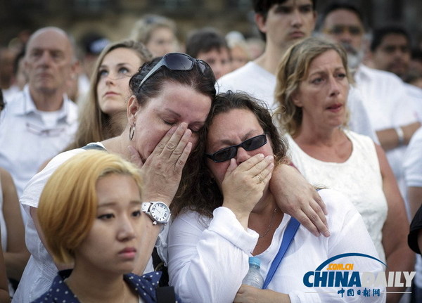当地时间7月23日,荷兰阿姆斯特丹,全国哀悼日当天,民众穿白衣悼念马航MH17客机遇难者,泣不成声。(图片来源:东方IC)