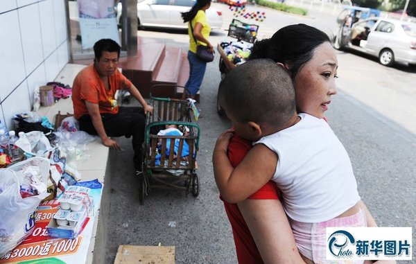 2014年7月26日，北京市房山区良乡华冠购物中心附近，金花和母亲彩虹一样呆滞无神地盯着满大街的人群，似乎她和若干兄弟姐妹们的命运已然无法改变。金花回家后，季女士（前）已来看过她多次。
