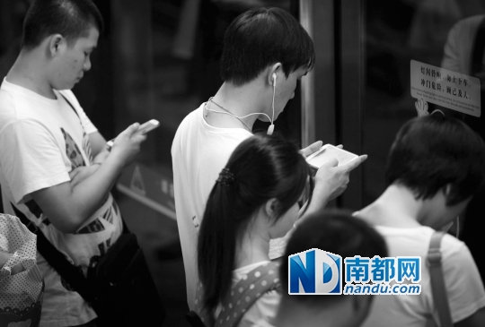 ↑候车区内,一群低头看手机的乘客。