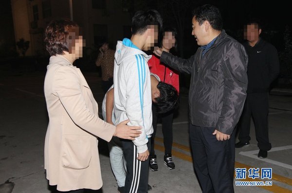 2014年9月18日深夜，山东临沂，返回临沂的两个孩子被家人领走，向刑警鞠躬道谢。图片：cfp