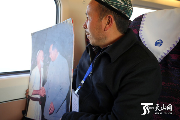 亚生·买买提明拿着爷爷跟毛主席的画像坐在窗前深思。