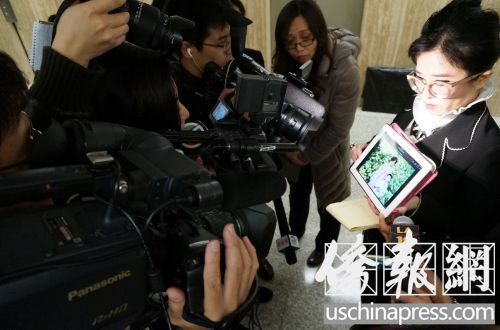 律师蔡玟慧通过图片在向媒体展示纪欣然的童年。（美国《侨报》/邱晨摄）