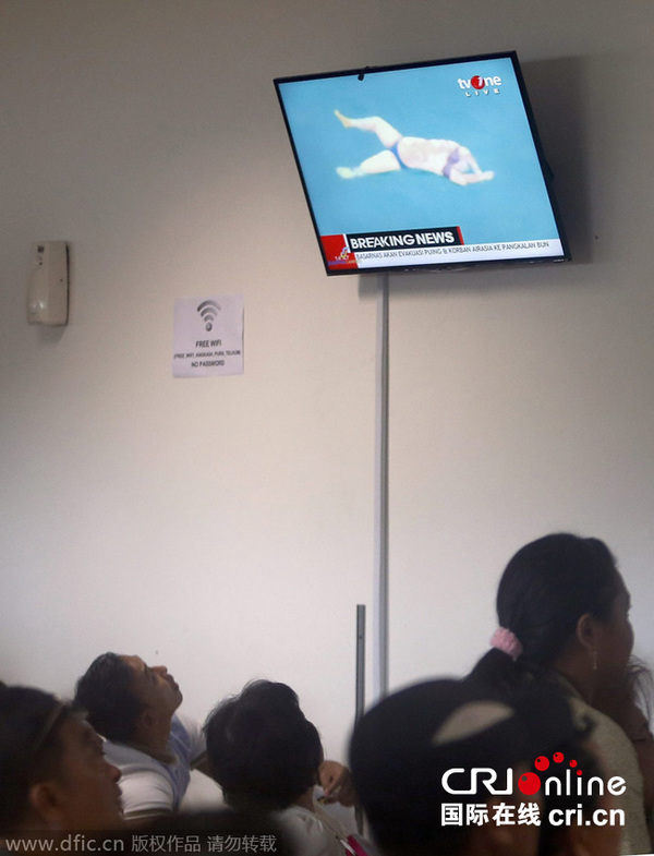 　　当地时间2014年12月30日，印尼泗水，失联亚航QZ8501航班乘客家属正在当地朱安达机场收看现场救援画面。图为电视画面播放搜救人员打捞一具未着救生衣的遗体。图片来源：东方IC