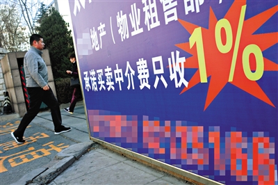 2014年3月20日，一小区门口贴着房产中介的宣传广告。新京报资料图片/记者浦峰摄