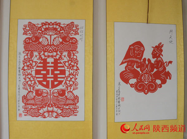 左为《双双对对》、右为《拜天地》,学员习作,原作者高学敏,线条简洁,寓意深刻。 和冰/摄 前言:刘慧霞,人称白鹿霞子,非物质文化遗产剪纸传承人。祖籍陕西关中腹地白鹿原,襁褓中随父母迁居西安莲湖区,醉心于剪纸艺术,其作品被认为杂糅汉代石刻写意手法,线条舒展、形态优雅。她的剪纸技艺在保留传统民俗剪纸原生态的基础上形成自己独立的艺术风格。她在西安市莲湖区残联兴办剪纸艺术工作室,倾囊相授,诲人无数,编纂有剪纸艺术技能培训教材。 一把金色手柄的小剪刀,红纸在指尖翻飞,细碎的小纸屑簌簌飘落不到1分钟,栩栩如生