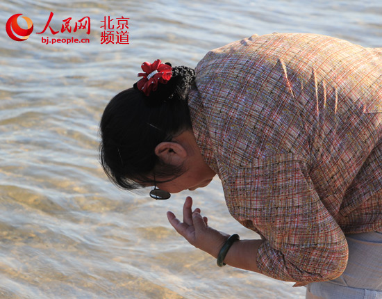 “青春河边巢”热心公益，在“带着盲人去旅行听海”活动中，小锟爸爸杨青锟拍下了一个盲人大姐用嘴“看”海的照片。图片由“青春河边巢”提供。