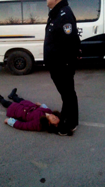 资料图：一名身穿警服的男子疑似用脚踩着周秀云的头发。新华社发