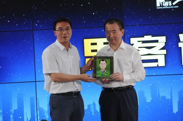 王健林接受新华网足球队赠送礼物 在足球上签