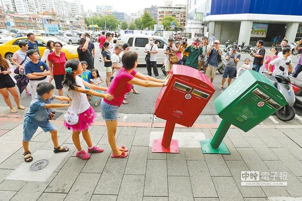 台北市龙江路口的邮筒，被苏迪勒台风刮下的招牌击中，成了“歪腰邮筒”萌样爆红，大批民众排队与它们合照，邮局另派邮差维持秩序。（黄世麒摄） 图片来源：台湾《中时电子报》