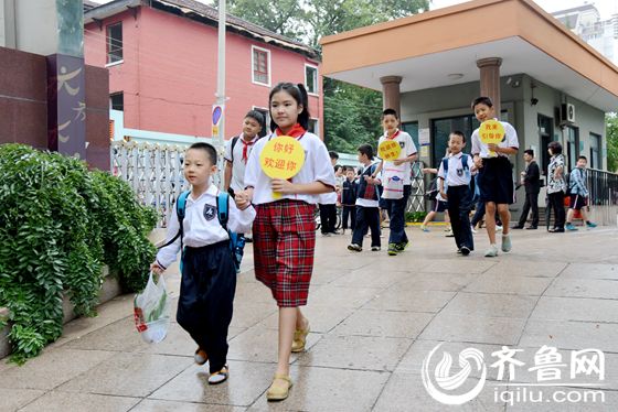 山师附小的高年级学生举着"欢迎牌"在校门口迎接低年级小学生入校.