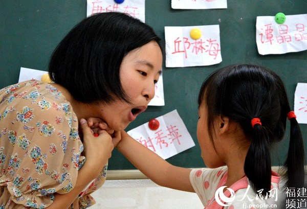 课堂上,王超拉过一名孩子的手捂住自己的喉咙,让孩子感受发音的状态。李挺摄