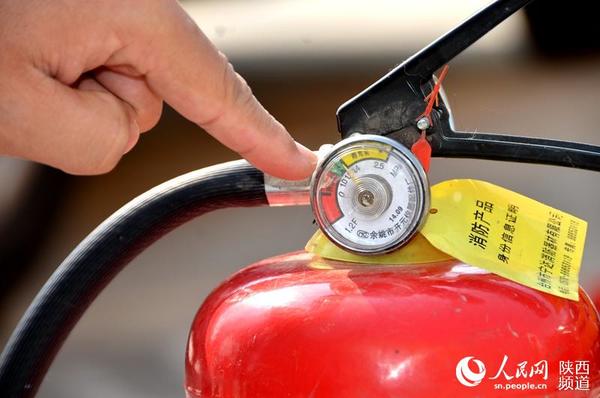查看灭火器压力。庞铭 摄