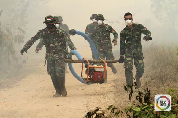 　　图为印尼士兵在灭火现场运送一台抽水泵。（图片来源：新华/路透）