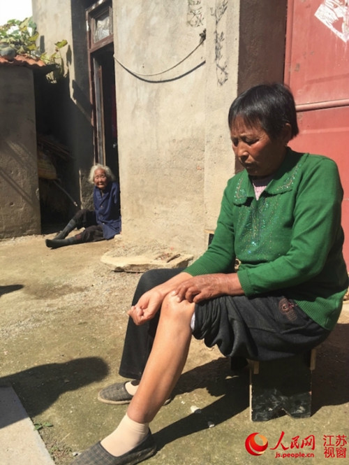 当事人乔桂云手上和膝盖被婆婆抓伤，神志不清的婆婆坐在房屋门口。