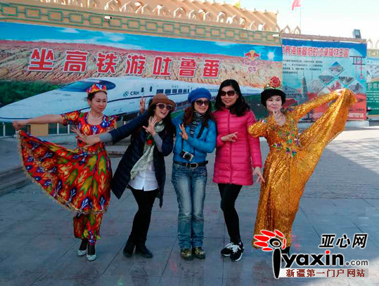 吐鲁番游客服务中心的员工跳起欢快的麦西来甫庆祝公司门票销售突破亿元大关，并与游客合影。
