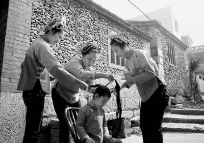 蟳埔阿姨给小姑娘梳头。