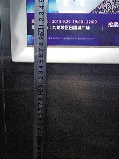 记者测量电梯广告牌高度。