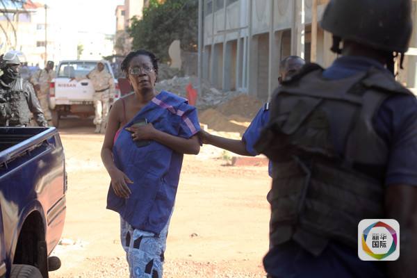 　　马里安全部队护送一名被解救的人质离开酒店。（图片来源：新华社/法新社）