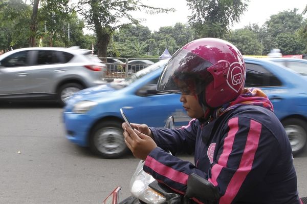 1月11日,印尼雅加达,一名女性摩的司机使用智能手机寻找顾客。(新华/路透)