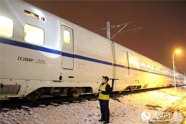 “动车保姆”在雪夜天气下检查动车组外部状态。（李磊 摄）