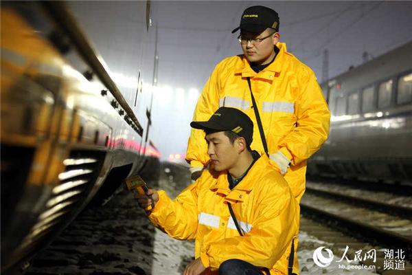 “动车保姆”在雪夜天气下对动车组关键部位进行点测温。（许辉 摄）