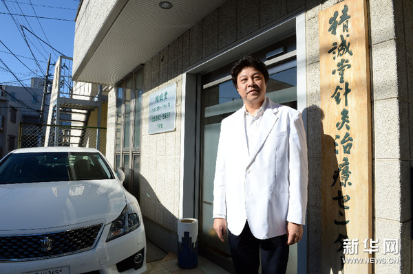 这是12月22日拍摄的贺伟与“精诚堂针灸治疗院”匾牌合影。新华社记者 马平 摄