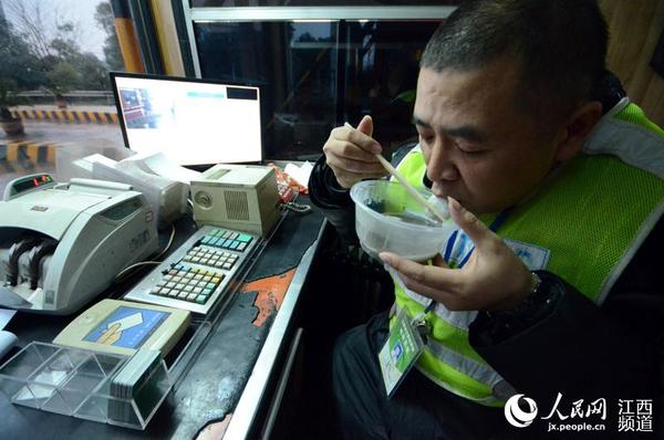 收费人员在收费亭内吃汤圆过元宵。