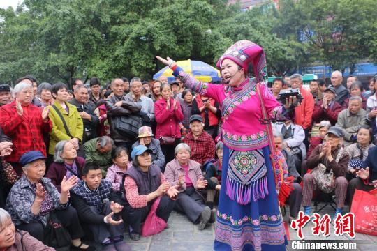 广西山歌王郭秀莲身着艳丽的民族服饰与市民进行山歌互动对唱,引来