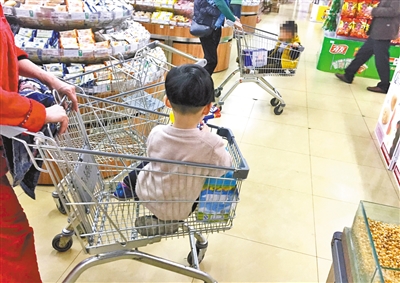 昨日,几位到超市购物的家长把孩子放在购物推车上。本报记者 杨新宇 摄