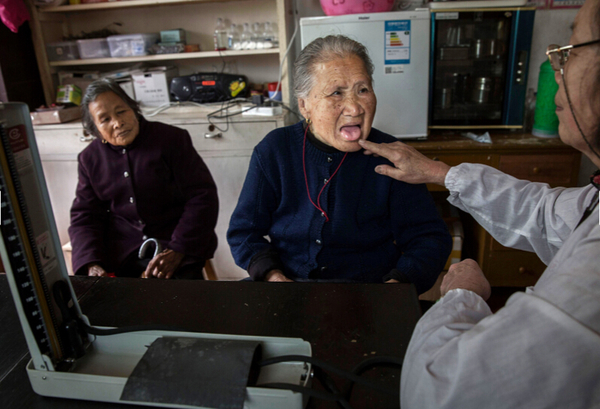 70岁的李来凤（Li Laifeng）已经在这里义务当了20年的医生，她正在为一位老人进行检查。（图片来源：美国在线）