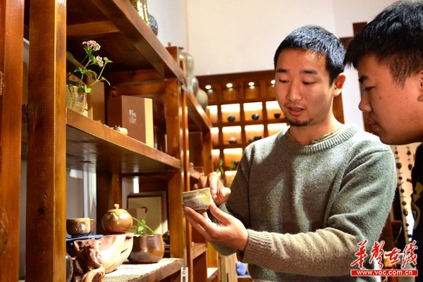 90后陶艺制作者刘嘉豪正在展示自己的作品。记者 龙腾 摄