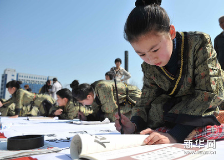 3月25日，少年书法爱好者在绍兴城市广场上书写毛笔字。新华网图片 袁云 摄