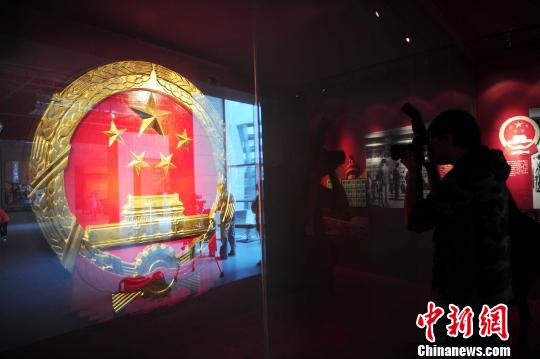 图为参展者在观看沈阳复制的新中国第一枚国徽。　于海洋　摄