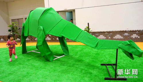 6月3日，小朋友在江苏省苏州国际博览中心观看巨型纸恐龙。新华网图片 陈煜 摄