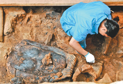 考古人员在“百戏俑”坑清理一件无头陶俑。新华社记者 李一博摄