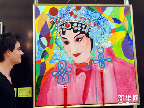 6月16日，一名外国参观者在国际少儿美术中国传统文化展上欣赏绘画作品。新华网图片 王建康 摄