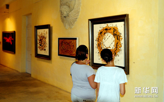 8月23日，在马耳他首都瓦莱塔，参加艺术展开幕式的嘉宾欣赏展出作品。新华网图片 刘宇 摄