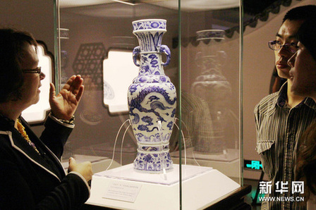 10月18日，英国大英博物馆工作人员（左）向参观者介绍珍贵的“至正十一年铭青花云龙纹象耳瓶”。新华网图片 许晟 摄
