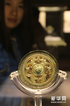 11月15日，一名观众在欣赏战国时期的“嵌玉绿松石钮变形龙纹镜”。新华网图片 任珑 摄