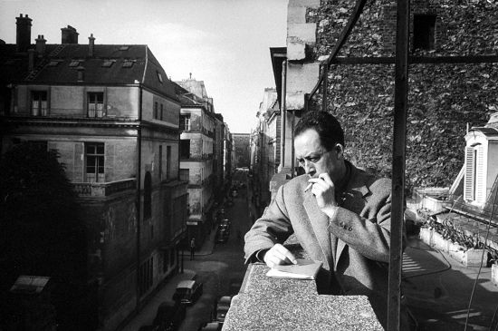 1913年11月7日出生的法国小说家、哲学家加缪，其文学作品的主题多为反抗暴力。图为1955年1月，加缪在出版公司办公室的阳台上抽烟。