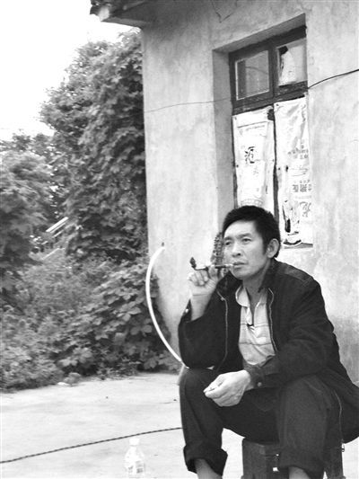 9月12日，陈文才在自己的出租屋旁抽烟。新京报记者 朱柳笛 摄
