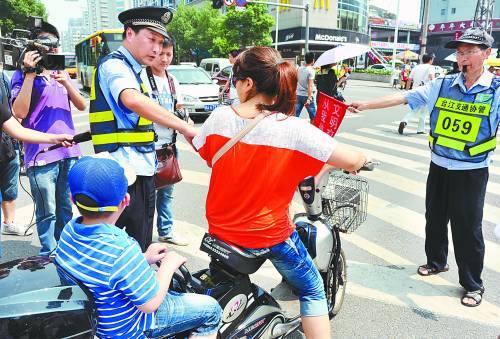 6月1日,福州,一名骑电动车带着孩子的家长在过马路时闯红灯被警察拦下